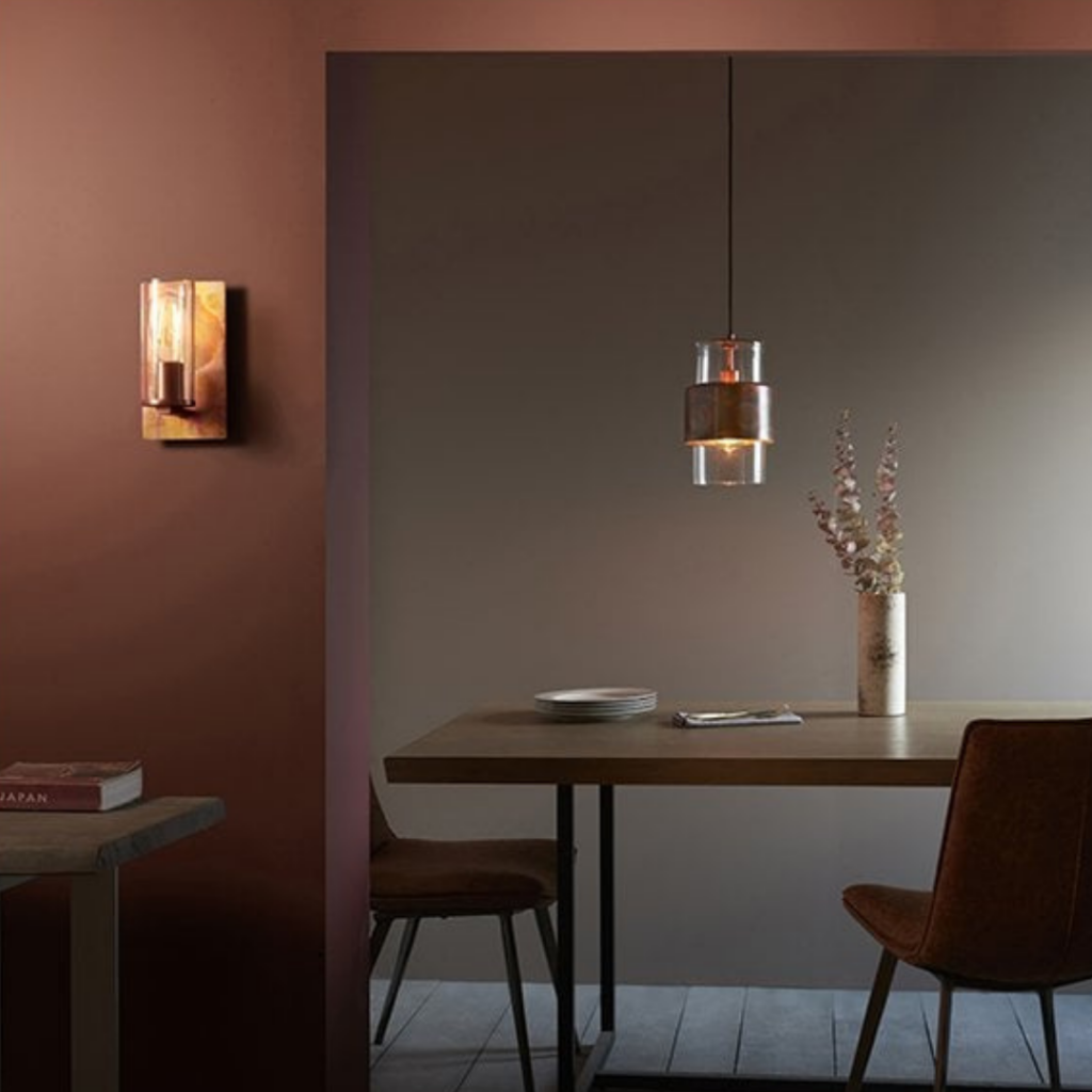 The Lenker wall light by Exemplar has an industrial, artisan design. The elegant, antique copper patina back plate has been paired with a clear glass and antique brass lamp holder, which reflects a warm glow across the wall and room.