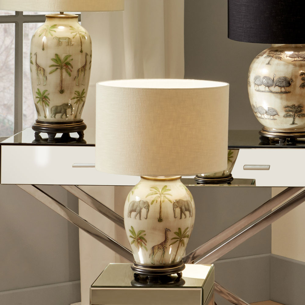 safari glass table lamp decorated with animals and cream drum shade