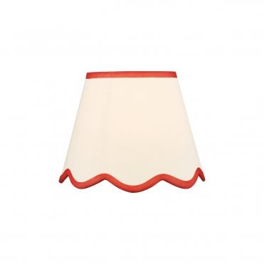 A neutral scalloped edge table lamp shade with red accent edging