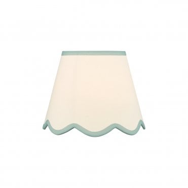 A neutral scalloped edge table lamp shade with blue accent edging